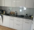 Modern kitchen with white cabinets, stainless steel sink, and various appliances on the counter.