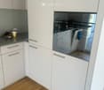 Modern kitchen with white cabinets, stainless steel appliances, and wooden flooring.