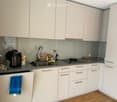 Modern kitchen with white cabinets, stainless steel sink, stove, and various appliances on the counter.