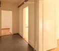 Empty room with dark grey tiled floor, white walls, and large white sliding doors leading to another space.