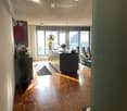 Open-plan kitchen and dining area with wooden flooring, modern kitchen island, pendant lighting, and large windows leading to a balcony.