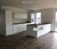 Modern kitchen with white cabinets, a central island, and wooden countertops, featuring a sink and faucet.