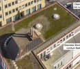 Aerial view of a multi-story building with a rooftop area featuring a small garden and round balconies.