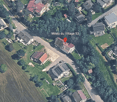 Aerial view of a residential area with multiple houses, surrounded by greenery and roads.