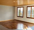 Empty room with wooden flooring, light-colored walls, and large windows with wooden frames. No furniture or equipment present.