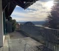 Balcony with metal railing, tiled floor, and scenic view of mountains and countryside.