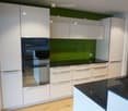 Modern kitchen with white cabinets, stainless steel oven, black countertop, and sink.