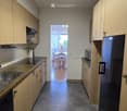 Modern kitchen with wooden cabinets, stainless steel sink, and appliances. Open to a dining area with a table and chairs.