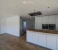 Modern kitchen with white cabinets, wooden countertop, and built-in oven. Large window offers a view of the outdoor area.