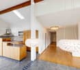 Modern kitchen with wooden cabinets, stainless steel range hood, central island, and large pendant lights.