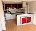 Modern kitchen with white cabinets, stainless steel appliances, and a central island with red accents.