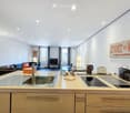 Open-plan living and kitchen area with modern furniture, including a sofa, coffee table, TV, and a kitchen island with appliances.