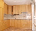 Bright kitchen with light wooden cabinets, granite countertops, and tiled backsplash. Features a sink with a modern faucet and built-in storage drawers.