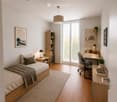 Modern bedroom with a wooden bed, nightstand, desk, and large window with blinds. Includes a bookshelf, potted plants, and decorative items.