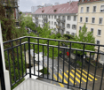 Balcony overlooking a city street with buildings, trees, and bicycles parked along the sidewalk.