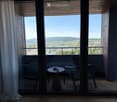 Balcony with a round table and two chairs, overlooking a scenic landscape with hills and cityscape.