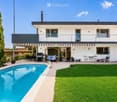 Modern two-story house with a swimming pool, patio furniture, and a well-maintained lawn.