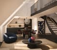 Modern, open-concept living and dining area with a sleek, dark wood floor, a blue velvet sofa, a round coffee table with decorative vases, a dining table with red chairs, and a contemporary kitchen area with dark cabinets and a pendant light.
