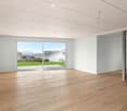 Empty room with light wooden flooring, white walls, and large glass doors leading to a view of a green lawn and distant houses.