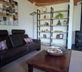 Modern living room with a dark leather sofa, wooden coffee table, floor lamp, bookshelf, and a fireplace.