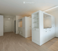 Modern, minimalist room with light wooden flooring, white walls, and built-in white cabinets and shelves.