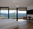 bedroom with large windows, balcony, wooden floor, bed, bench, TV, outdoor table and chairs