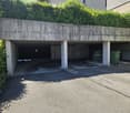 Underground garage with multiple parking spaces, concrete pillars, and greenery on the roof.
