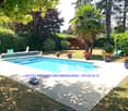 Well-maintained garden with a swimming pool, surrounded by potted plants, lounge chairs, and a wooden shed.