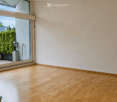 Empty room with wooden flooring, large windows, and a view of the outdoor area.