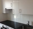 Modern kitchen with white cabinets, black countertops, stainless steel sink, and built-in oven.