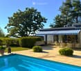 Outdoor patio area with a swimming pool, lounge chairs, dining table, and surrounding greenery.