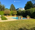 Well-maintained garden with a swimming pool, surrounded by greenery, potted plants, and a lounge chair.