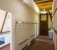 A hallway, white walls, wooden ceiling, kitchen on left, hallway lamp, closed wooden door