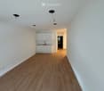 Empty hallway with wooden flooring, white walls, and white cabinetry in the background. No furniture or personal items present.