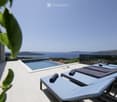 A modern rooftop terrace with a swimming pool, sun loungers, and a stunning sea view.