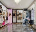 Modern salon interior with sleek black and white decor, large mirrors, mannequins displaying hair pieces, and stylish chairs.