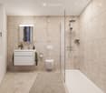 Modern bathroom with beige tiles, a white sink with a mirror, a toilet, a bathtub with a glass shower enclosure, and a towel hanging on the wall.