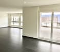 Empty room with dark tiled floor, white walls, large windows, and sliding glass doors leading to a balcony.