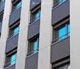 Modern building with multiple floors, each floor has a balcony, white walls, and gray railings