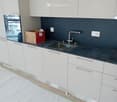 modern kitchen, white cabinets, gray countertop, stainless steel sink, faucet, electrical outlets, cardboard box, white floor