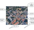 Aerial view of a residential and commercial area with labeled landmarks including a primary school, sports center, tram stop, hospital, and CERN.
