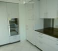 Modern kitchen with light grey cabinets, stainless steel oven, and black countertop.