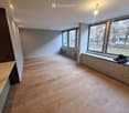 Empty room with wooden flooring, large windows, and built-in bench seating along one wall.