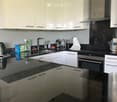Modern kitchen with white cabinets, black countertops, stainless steel appliances, and a central island.