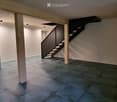 Empty room with tiled floor, white walls, and a staircase leading upwards. No furniture or equipment present.