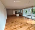 Empty room with wooden flooring, large windows, and a view of the balcony area.