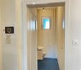 Small bathroom with blue tiled floor, white walls, a sink, toilet, and a towel hanging on the side.