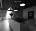 Modern kitchen with white cabinets, black countertop, stainless steel sink, and pendant lights. A vase with flowers is placed on the counter.