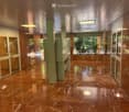 Spacious hallway with polished marble floors, marble walls, recessed lighting, and glass doors leading to outdoor areas.