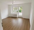 Empty room with wooden flooring, white walls, and a radiator under a window. No furniture or equipment present.
